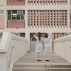 two people standing on a bridge in front of a building