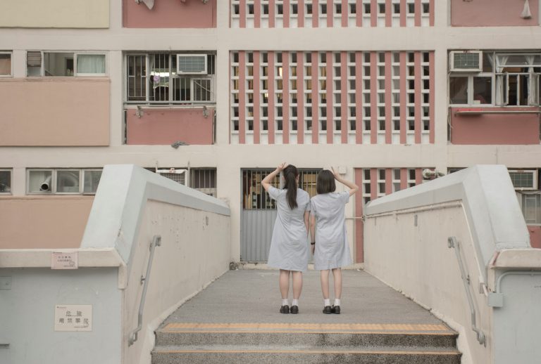 香港青少年的成長路徑與次文化演變 two people standing on a bridge in front of a building