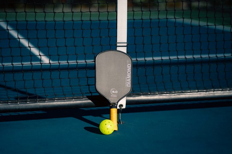 Pickleball的魅力:探索這項運動及其必備配件 A tennis racket and ball on a tennis court