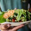 a person holding a bowl of salad with lettuce and tomatoes