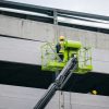 a man on a scissor working on the side of a building